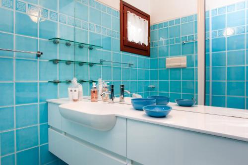 a blue tiled bathroom with a sink and a mirror at Villa Briziola in San Teodoro