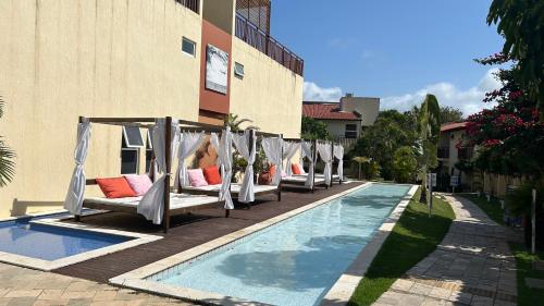 a row of beds with pillows next to a pool at Loft Solar Água in Pipa