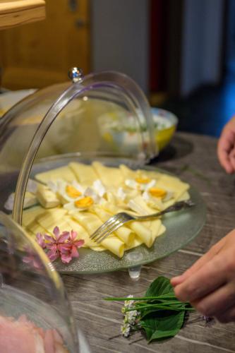 a plate of cheese on a table with a fork and knife at Flora - Das kleine Gartenhotel in Ellmau