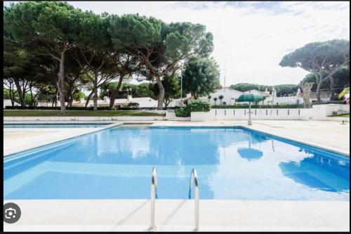 une grande piscine bleue avec des arbres en arrière-plan dans l'établissement Casa Calma, à Albufeira