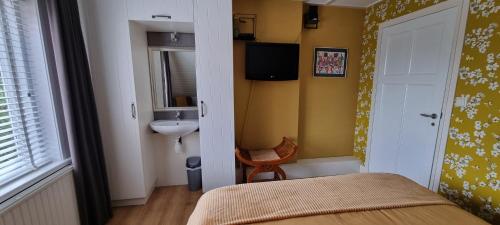 a bedroom with a bed and a sink and a mirror at B&B MaasLandje in Wijk en Aalburg