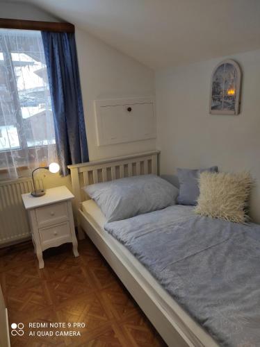a bedroom with a bed and a nightstand and a window at Haus Mühlenheim in Schwendau
