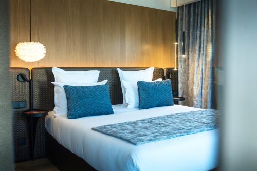 a bedroom with a large bed with blue pillows at Le Pélican in Annecy
