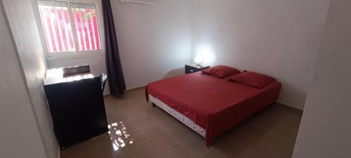 een kleine slaapkamer met een rood bed en een raam bij Les chambres du Manguier in Mamoudzou
