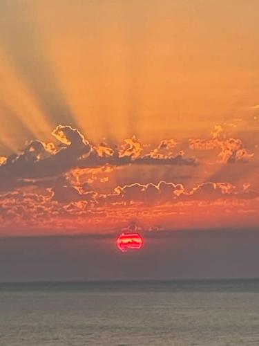 a sunset over the ocean with a red object in the sky at Melianto House in Mithymna