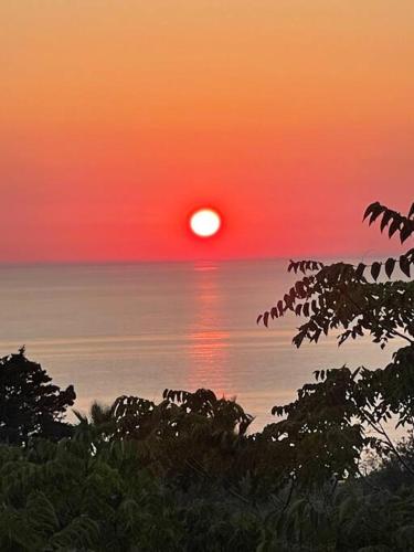 a sunset over the ocean with the sun in the distance at Melianto House in Mithymna