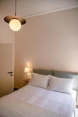 a bedroom with a bed with white sheets and a lamp at Faedra Residence in Chania Town