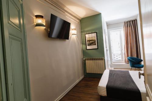 a room with a bed and a tv on the wall at Hôtel du Dauphin in Lyon