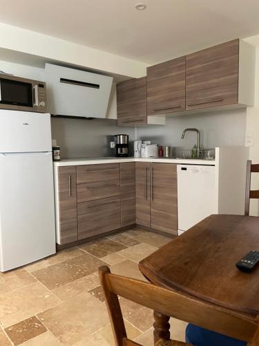 a kitchen with a wooden table and a white refrigerator at Cinégîte du jardin aux étoiles - Proche de Saint Emilion in Saint-Pey-de-Castets