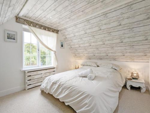 a bedroom with a large white bed with a wooden ceiling at Sweetpea Cottage in Hambrook