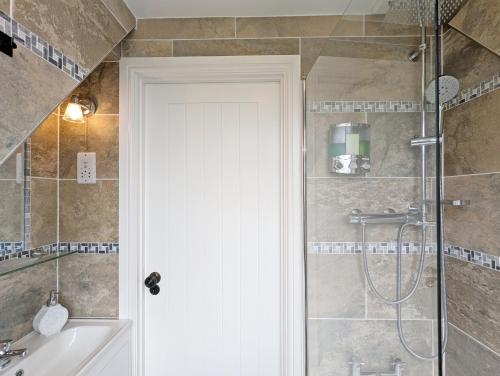 a bathroom with a shower with a tub and a sink at Sweetpea Cottage in Hambrook