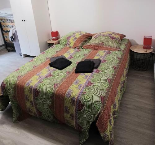 ein Bett in einem Zimmer mit zwei schwarzen Gläsern darauf in der Unterkunft Petite maison cosy wifi avec terrasse in Montigny-le-Gannelon