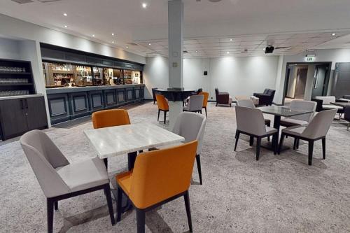 a restaurant with tables and chairs and a bar at Village Hotel Cardiff in Cardiff
