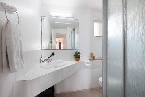 Baño blanco con lavabo y espejo en Santorini Perissa Seaview Apartment en Shakaskraal