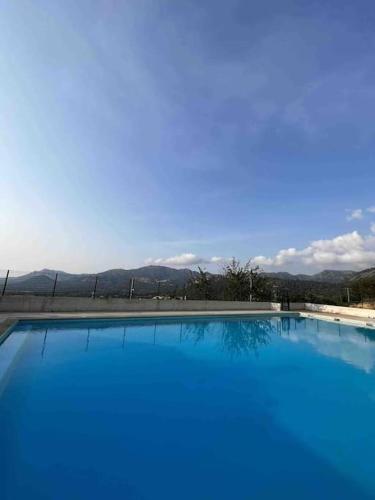 une grande piscine bleue avec des montagnes en arrière-plan dans l'établissement Appartement rénové entre terre et mer avec piscine, à Calenzana