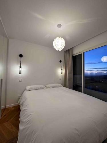 - une chambre avec un lit blanc et une grande fenêtre dans l'établissement Appartement rénové entre terre et mer avec piscine, à Calenzana