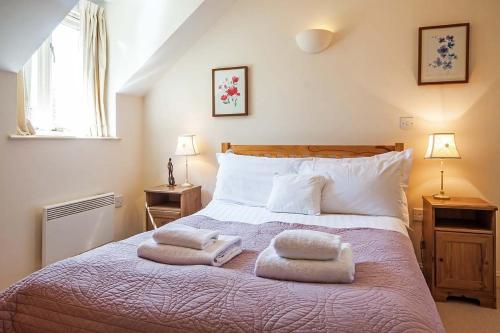 a bedroom with a large bed with two towels on it at Mill Village 59, Millstream Cottage - P in Somerford Keynes
