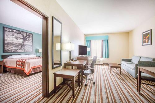 a hotel room with a bed and a desk and a bedroom at Super 8 by Wyndham Port Arthur/Nederland Area in Port Arthur