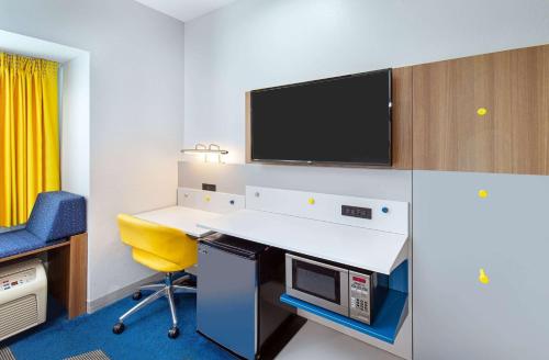 an office with a desk and a tv on a wall at Microtel Inn and Suites by Wyndham in Opelika