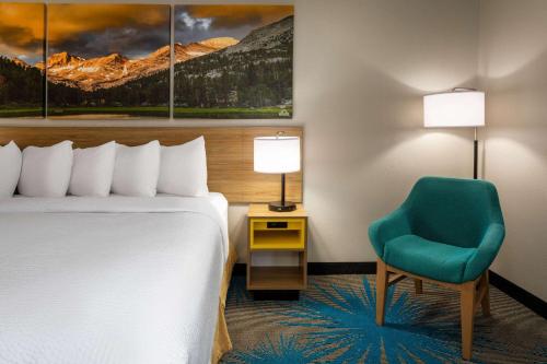 a hotel room with a bed and a chair at Days Inn & Suites by Wyndham Denver International Airport in Denver