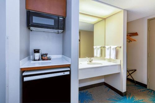 a bathroom with a sink and a microwave at Days Inn & Suites by Wyndham Denver International Airport in Denver