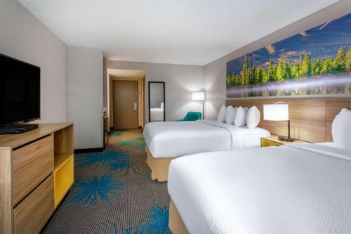 a hotel room with two beds and a flat screen tv at Days Inn & Suites by Wyndham Denver International Airport in Denver