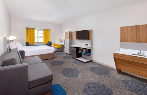 a hotel room with a bed and a couch at Microtel Inn and Suites by Wyndham in Opelika