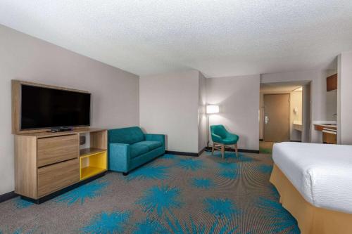 a hotel room with a bed and a flat screen tv at Days Inn & Suites by Wyndham Denver International Airport in Denver