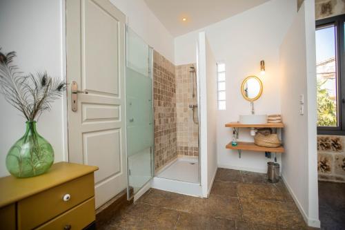 a bathroom with a shower and a vase on a table at Oustaou de Betty et Bob in Le Cailar