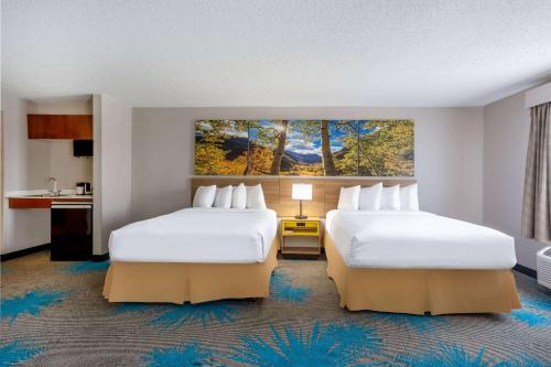 um quarto de hotel com duas camas e um quadro na parede em Days Inn & Suites by Wyndham Denver International Airport em Denver