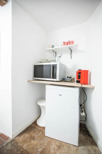 Il comprend une cuisine blanche équipée d'un four micro-ondes et d'un réfrigérateur. dans l'établissement Oustaou de Betty et Bob, à Le Cailar