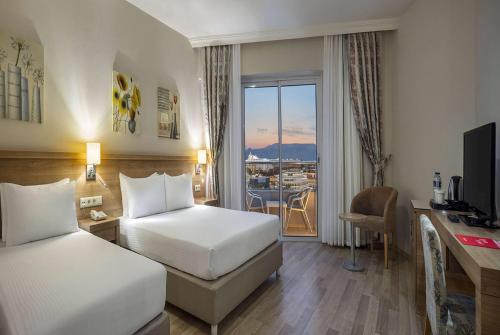 een hotelkamer met 2 bedden, een bureau en een raam bij Ramada Resort By Wyndham Lara in Lara