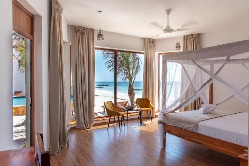 a bedroom with a bed and a view of the beach at S&S HOTEL in Jambiani