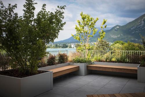 a garden with two benches and trees on a balcony at Le Pélican in Annecy