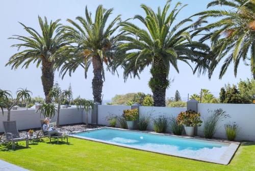 een achtertuin met een zwembad en palmbomen bij Four Palms Accommodation in Durbanville