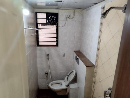 a small bathroom with a toilet and a window at JUST HOME 2BHK in Pune