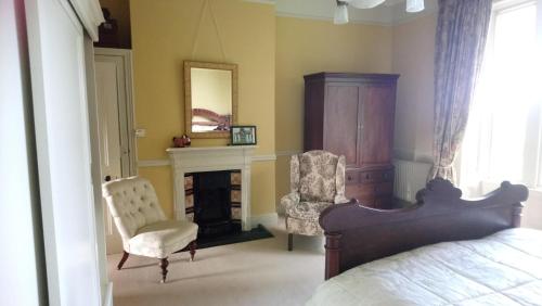 a bedroom with a bed and a chair and a fireplace at Templemacateer B&B in Westmeath