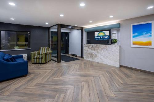 a lobby with a blue couch and a tv on a wall at Days Inn by Wyndham Pleasant Prairie Kenosha in Kenosha