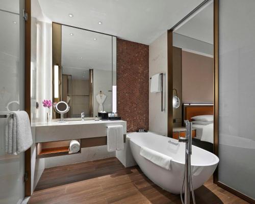 uma casa de banho com uma banheira, um lavatório e um espelho. em Hyatt Regency Shanghai Songjiang em Songjiang