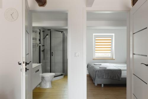 a white bathroom with a bed and a shower at Apartamenty FILIP w Kudowie-Zdroju in Kudowa-Zdrój