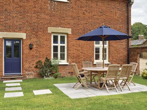 a table and chairs with an umbrella in front of a brick building at Bridge House at Woodhall Estate in Hertford