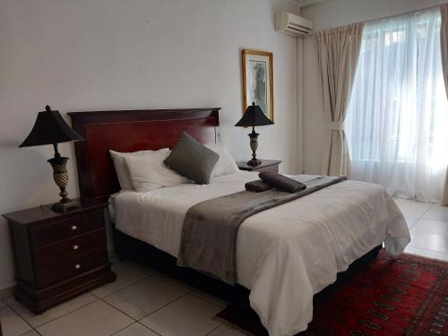 a bedroom with a bed and two lamps and a window at The Goldstone in Pretoria