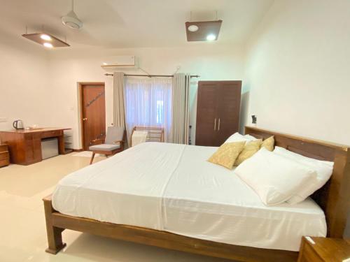 a bedroom with a large bed and a desk at New Sea Villa in Negombo