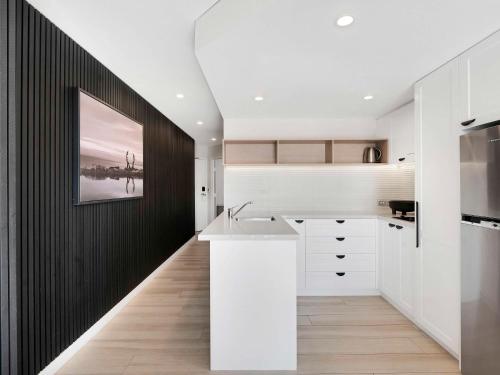 a kitchen with white cabinets and a black wall at Peppers Manly Beach in Sydney