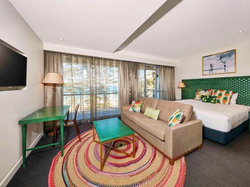 una camera con letto, divano e tavolo di Peppers Manly Beach a Sydney