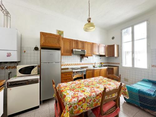 eine Küche mit einem Tisch und einem weißen Kühlschrank in der Unterkunft CASA DI LUCA - Le Sorelle - A 1 Minuto Dal Centro in Sanremo
