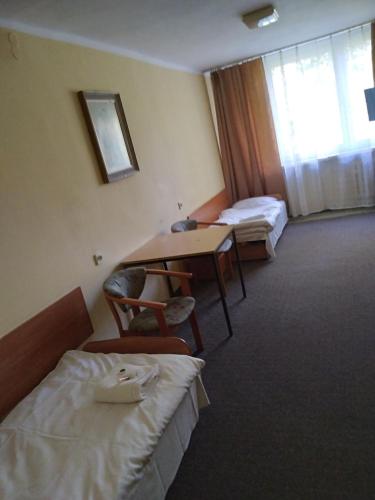 a hotel room with two beds and a table and a desk at CKS Kraków (Centrum Konferencyjno-Szkoleniowe CS Natura Tour) in Kraków