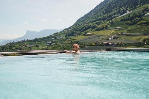 a woman in a hot tub with mountains in the background at Hotel Dorner B&B in Lagundo
