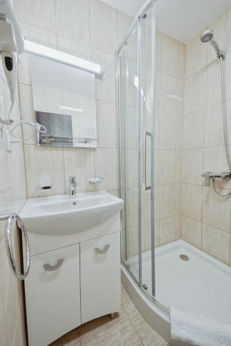 a white bathroom with a sink and a shower at Complex Turistic Constantin Bucovina in Câmpulung Moldovenesc