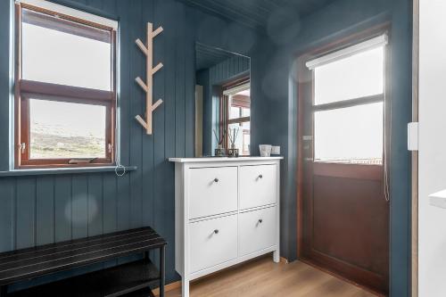 a blue room with a white cabinet and two windows at The Angels House in Selfoss